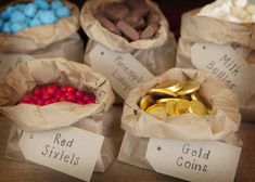 four bags filled with different types of gold coins and chocolates on top of a table