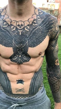 a man with an eagle and skulls tattoo on his chest is standing in the grass