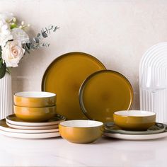 a table topped with yellow dishes and white flowers