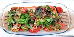 a glass casserole dish filled with lots of vegetables and toppings on top