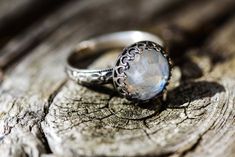 This is a cool and mysterious-looking moonstone ring. The stone is 10mm in size. The stone is a genuine moonstone with a hint of blue chatoyance and it seems to glow from within...and maybe you'll receive a stone with a rainbow in it! Choose your size from the pulldown menu when you check out. The beautiful flowery setting has been handcrafted by me out of sterling wire and has a crown 10mm sterling silver setting. The band is about 3.5mm wide. You may choose the lightly antiqued finish, polishe Mystical Moonstone Birthstone Ring, Mystical Cabochon Moonstone Ring, Mystical Handmade Moonstone Ring, Mystical Moonstone Cabochon Ring, Mystical Round Handmade Moonstone Ring, Mystical Handmade Round Moonstone Ring, Elegant Handmade Moon Crystal Ring, Mystical Moonstone Ring With Cabochon Cut, Elegant Handmade Moon-shaped Crystal Ring