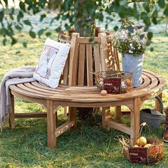 a wooden bench sitting on top of a grass covered field next to flowers and potted plants