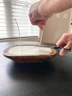 a person cutting into a cake on top of a wooden plate with two knives in it