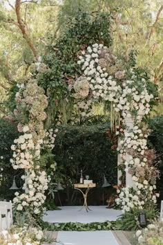 an outdoor ceremony with white flowers and greenery