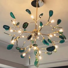 a chandelier with green leaves hanging from it's center point in a living room