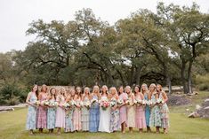 a group of women standing next to each other in front of trees