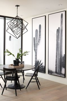 a dining room table with four chairs in front of three large cactus pictures on the wall