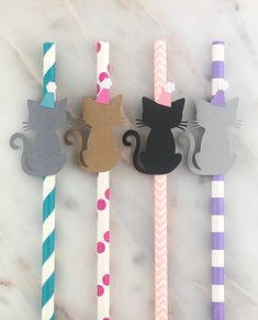 four paper straws with cats on them sitting next to each other in front of a marble surface