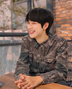 a young man sitting at a table smiling