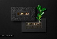 a black business card with gold foil lettering and a green plant on the bottom right corner