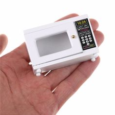 a hand holding a small white microwave oven