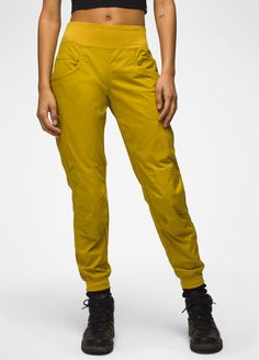 the woman is wearing yellow pants and black shoes with her hands in her pockets,