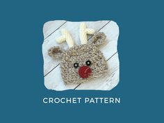 a crocheted reindeer hat with red nose and antlers on the side, sitting on a wooden surface