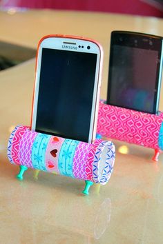 a cell phone sitting on top of a pink and blue holder next to another device