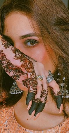 a woman with henna tattoos covering her face and hands is posing for the camera