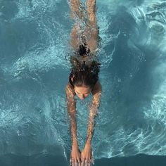 a woman is swimming in the pool with her hands on her hips and head above water