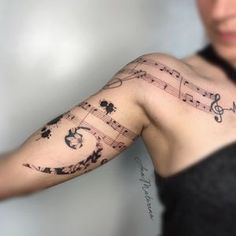 a woman's arm with musical notes and flowers on the left side of her arm