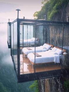 a couple of beds sitting on top of a wooden platform next to a body of water