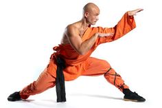 a man in an orange outfit is doing martial moves with his hands out to the side