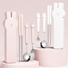 an assortment of utensils and spoons are arranged on a pink stand with bunny ears