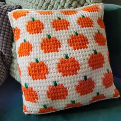 a crocheted pillow with orange pumpkins on it sitting on a blue chair