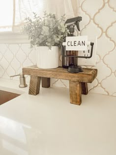 a kitchen counter with a sign that says clean and a potted plant on top