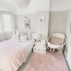 a bedroom with a pink rug and white bedding, hanging hammock in the corner