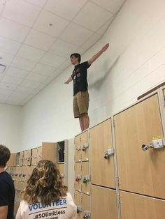 a man standing on top of a stack of lockers in a room filled with people