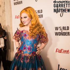 a woman with long red hair wearing a blue and pink dress on the red carpet