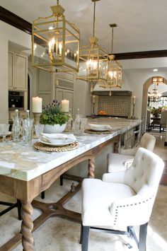 a dining room table and chairs with candles on it in front of a kitchen island