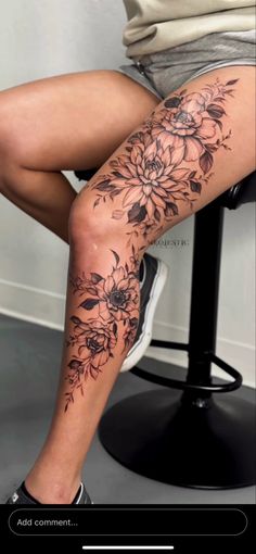 a woman sitting on top of a chair with her legs covered in tattoos and flowers