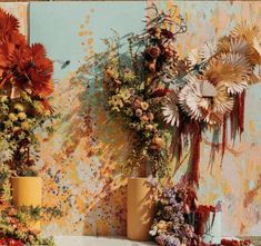 two vases filled with flowers sitting next to each other on a table in front of a wall