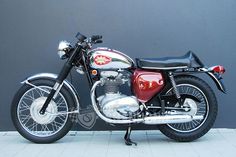 a red and black motorcycle parked in front of a gray wall