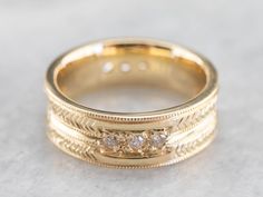 This engraved band is of a perfect heft and shape to feel soft and pleasant on the finger. It is both pretty and sophisticated, and it would be a great wedding or stacking band for a woman who wants a little extra sparkle but works with her hands. Metal: 18K Yellow Gold Gem: 12 Diamonds totaling .36 Carats, F in Color, VVS in Clarity Width of Band: 6.5 mm Height off Finger: 1.9 mm Ring Size: 6 Marks: "AA18K" Stamped on the inside band Heirloom Yellow Gold Bands With Decorative Details, Gold Milgrain Round Band, Luxury Stackable Rings With Thick Band For Wedding, 14k Gold Bands With Diamond Accents, Heirloom 14k Gold Open Band, Fine Jewelry Wedding Rings With Milgrain Detail, Gold Milgrain Bands For Anniversary, Heirloom Diamond Ring With Decorative Band, Round Cut, Heirloom Round Cut Diamond Ring With Decorative Band