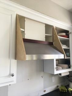 a kitchen with white cabinets and an open shelf above the stove top that has some bananas on it