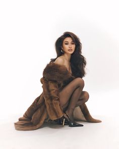 a woman sitting on the ground in a fur coat