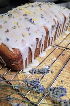 a loaf of cake with white icing and lavender sprinkles on a cooling rack