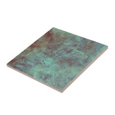 an image of a square tile with blue and green paint on the bottom, it is isolated against a white background