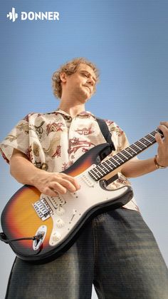 a man holding a guitar in his right hand and looking up at the sky behind him