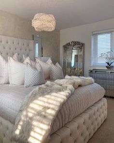 a large bed sitting in a bedroom under a chandelier