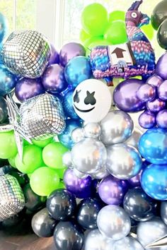 there are many balloons in the room and one is blue, green, purple and silver