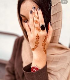 a woman with her hands on her face covered in hendik and holding her hand up to her face