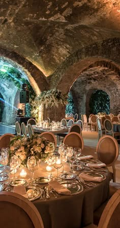 an indoor dining area with round tables, chairs and candles on the table in front of them