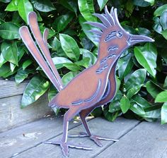 a metal bird sitting on top of a wooden deck