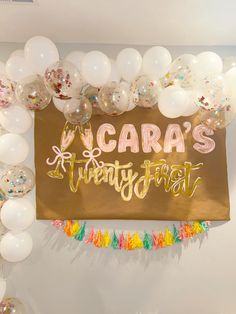 balloons and confetti surround the backdrop for a birthday party with acara's written on it