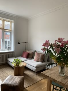 a living room filled with furniture next to a window covered in pink and white flowers