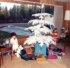 two children sitting in front of a christmas tree with presents on the floor next to it