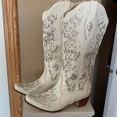 a pair of white cowboy boots with sequins on them sitting on a shelf