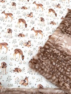 a blanket with deers and leaves on it is laying next to a stuffed animal