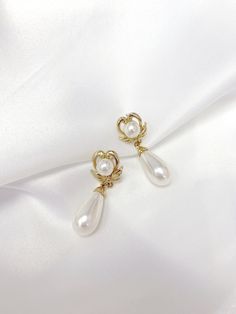 Vintage Inspired Earrings from the 1950s & 1960s. This beautiful Vintage Faux Pearl Classic Heart-Wing Drop Earrings are plated in Champagne Gold tone metal leading to a Classic style elongated white faux pearl tear drop. Earrings will be provided with Gold plated Butterfly backs. Items will be wrapped in a beautiful gift box.  Go Social : FOLLOW US ON INSTAGRAM : @RAQUEL.VINTAGE Gold Heart Shaped Clip-on Earrings For Wedding, Elegant Dangle Heart Earrings For Anniversary, Elegant Dangle Heart Earrings For Wedding, Elegant Heart-shaped Pearl Earrings For Party, Elegant Gold Heart-shaped Clip-on Earrings, Elegant Gold Heart Shaped Clip-on Earrings, Elegant Heart-shaped Clip-on Jewelry, Heart-shaped Clip-on Wedding Earrings, Wedding Heart-shaped Clip-on Earrings